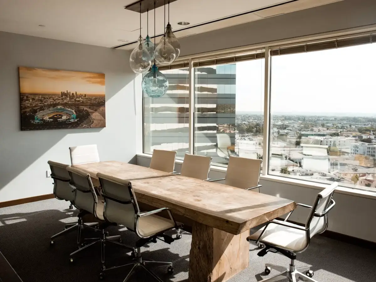 Sala de reunião envidraçada com mesa, cadeiras e vista pela janela